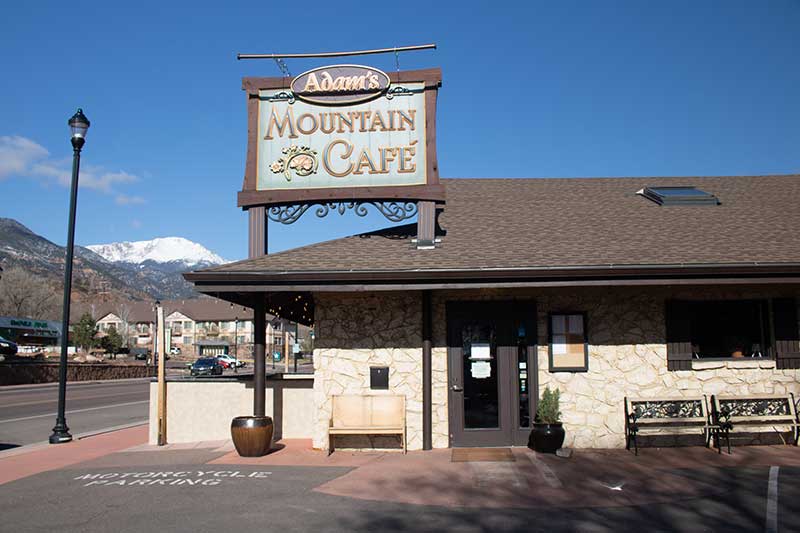 This photo shows Adam's Mountain Cafe with Pikes Peak in the background. Success Stories from the Manitou Springs Urban Renewal Authority. This photo shows Adam's Mountain Cafe with Pikes Peak in the background. Success Stories from the Manitou Springs Urban Renewal Authority.